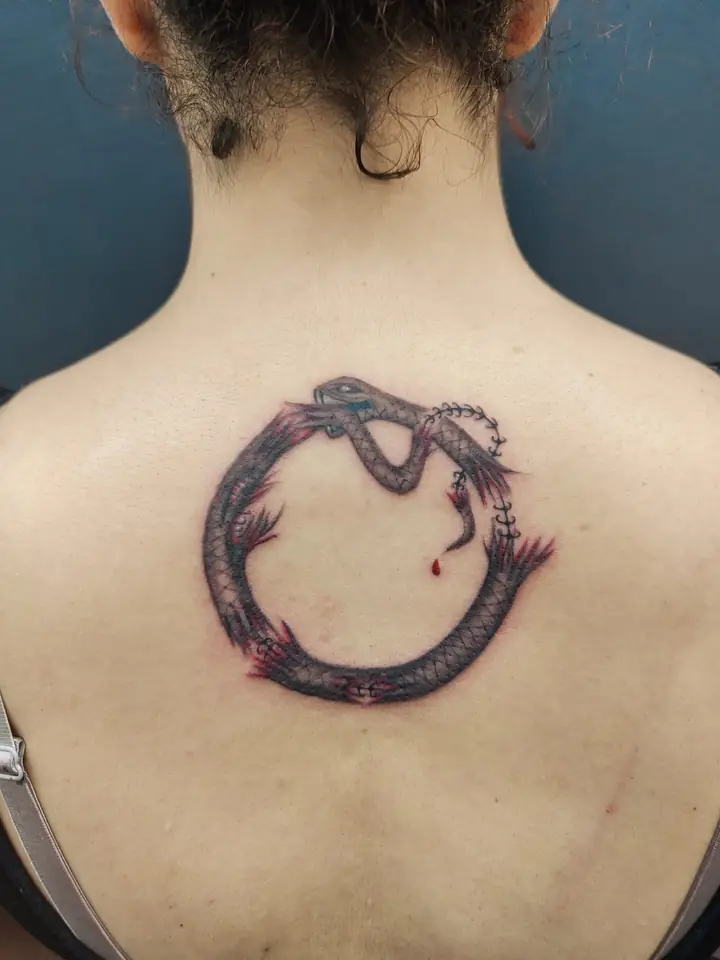 Ouroboros serpent circle tattoo between the shoulder blades